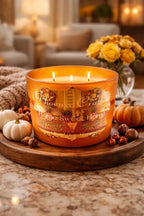 Home Sweet Home Candle on a wooden platter surrounded by autumn decorations and flowers in a cozy living space.