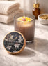 Honeysuckle Jasmine Candle in a glass jar, featuring a floral design, on a marble surface with towels and essential oils.