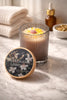 Honeysuckle Jasmine Candle in a glass jar, featuring a floral design, on a marble surface with towels and essential oils.