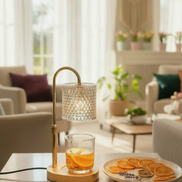 Brass table lamp with curved arm and textured glass shade over a clear tumbler holding orange slices.