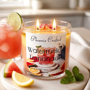 Clear glass jar candle with yellow-orange wax, three lit wicks and pink flower decorations on a round marble coaster with lemon and watermelon wedges.