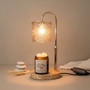 Chrome lamp warmer with patterned glass shade over a wood base holding an amber jar with white wax chunks; black remote.