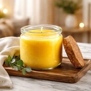 Island Citrus & Agave Candle in a glass jar with a cork lid, displayed on a wooden tray with greenery.