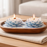 Island Orchard blue-and-white lotus-shaped decorative candles lit in an oval wooden bowl on a folded cream cloth.