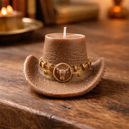Leather cowboy-hat-shaped decorative candle with gold chain detail and a bull-head emblem, styled on a rustic wood table.