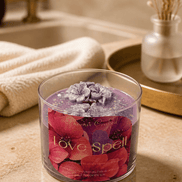 Love Spell Candle with purple wax and floral decorations, set in a stylish bathroom ambiance.