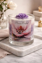 Magnolia Candle in a glass jar with floral design and purple flower on top, perfect for creating a calming atmosphere.