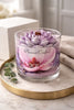 Phoenix Crafted Magnolia candle in a clear glass jar with a purple-and-white lotus-shaped wax topper and wooden wick on a marble tray.