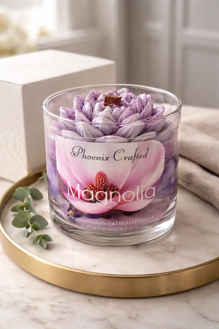 Phoenix Crafted Magnolia candle in a clear glass jar with a purple-and-white lotus-shaped wax topper and wooden wick on a marble tray.