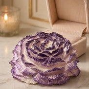 Magnolia Candle in a floral-shaped design, featuring purple and white layers, set on a marble surface with a candle.