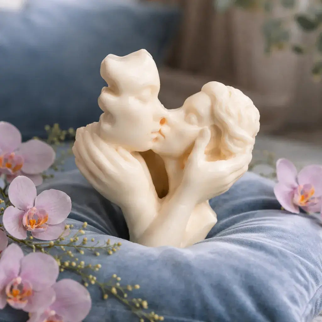 Decorative Mahogany Coconut Candles displayed with an elegant sculpture of two figures kissing, surrounded by flowers.