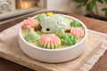 A decorative dessert featuring a hedgehog, flowers, and greenery, beautifully arranged in a white bowl.
