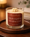 Mahogany Teakwood Candle in a glass jar on a wooden tray, showcasing its rich scent and design.