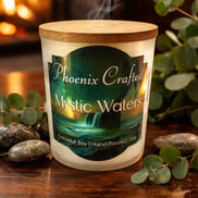 Mystic Waters Candle with a wooden lid, hand-poured coconut soy, surrounded by greenery and stones, burning softly.