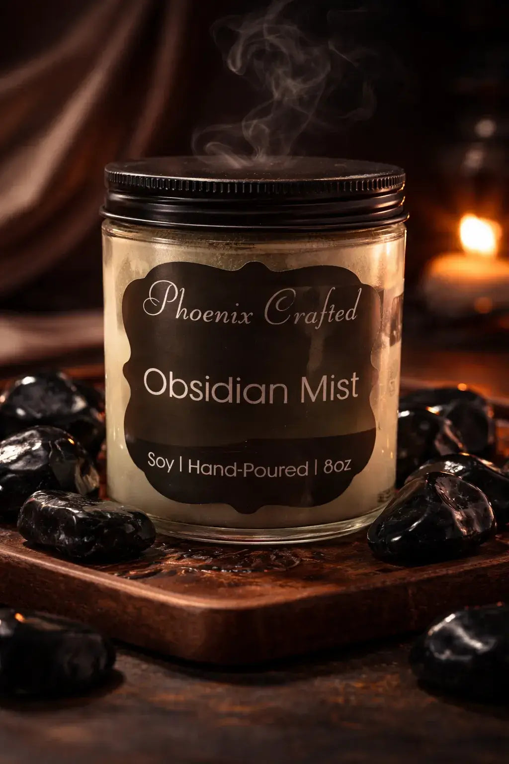 Obsidian Mist Candle in a glass jar with smoky fragrance, surrounded by polished obsidian stones.