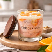 Orange Cream Candle in a glass jar with a wooden lid, featuring citrus and creamy layers, placed on a wooden tray.