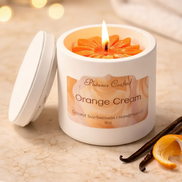 White jar candle labeled 'Phoenix Crafted Orange Cream' with lid beside it.