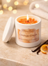 White jar candle labeled 'Phoenix Crafted Orange Cream' with lid beside it.