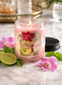 Orchid Mojito Candle in a clear jar, featuring fresh mint, lime, and a pink orchid on a marble surface.