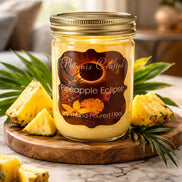 Pineapple Eclipse Candle in a glass jar surrounded by fresh pineapple on a wooden surface.