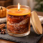 Lit Pumpkin Spice candle in a clear glass jar with a wood lid, styled with pumpkin, cinnamon, and star anise.