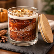 Clear glass jar candle with white wax and crumb-like topping bearing a label that reads Phoenix Crafted Pumpkin Spice.