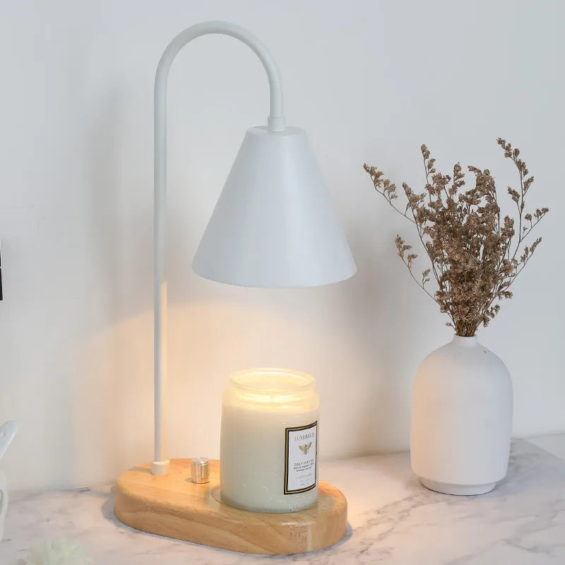 Electric candle warmer with wooden base illuminating a candle on a contemporary bedside table.