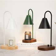 Three arched candle warmer lamps in white, green, and black with conical shades, shown with wood bases and jar candles.