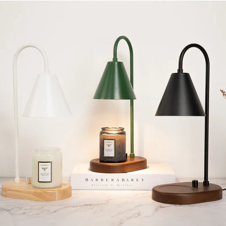 Three arched candle warmer lamps in white, green, and black with conical shades, shown with wood bases and jar candles.