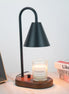 Black arched candle warmer lamp with a dark conical shade and round wood base, styled with a clear jar candle, books, and framed art.