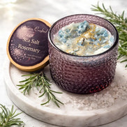 Sea Salt & Rosemary Candle in a textured glass holder on a marble surface, surrounded by fresh rosemary and sea salt.