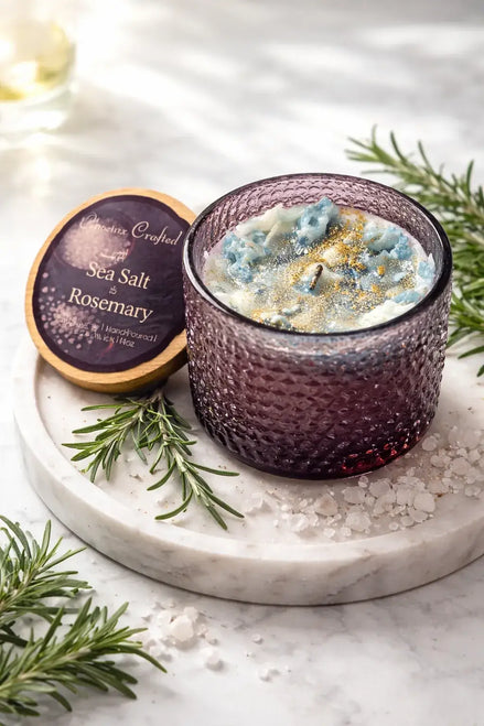 Sea Salt & Rosemary Candle in a textured glass holder on a marble surface, surrounded by fresh rosemary and sea salt.