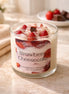 Strawberry Cheesecake Candle in a glass jar with fresh strawberries and chocolate pieces.