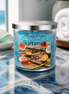 Summer Skinny Dip Candle in a stylish jar with tropical fruit design on a table by the sea.