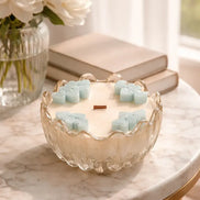 Teak & Mint Renewal Decorative Candles displayed beautifully on a marble table with flowers and books.