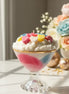 Tropical Sorbet Decorative Candles with colorful toppings in a glass, surrounded by flowers and soft lighting.
