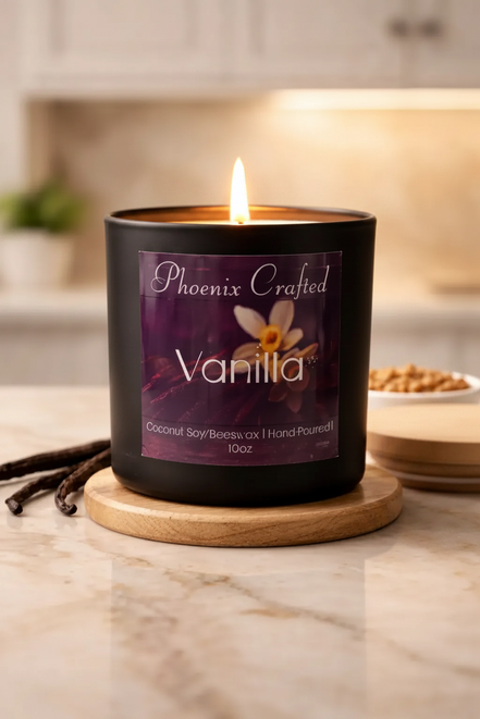 Matte black cylindrical candle jar with purple 'Phoenix Crafted Vanilla' label, lit single wick.