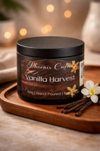 Vanilla Harvest Candle in a black jar on a wooden tray with vanilla pods and flowers.