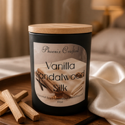 Black matte jar candle with pale lid on a round tray beside palo santo sticks, a dark pod, and a cream cloth.