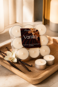 Vanilla Tealights in a pack with vanilla pods and a flower on a wooden tray, showcasing cozy candlelight.