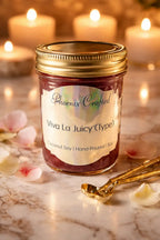 Viva La Juicy Candle in a hand-poured jar, featuring a vibrant label and surrounded by soft floral accents.