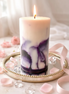 Viva La Juicy Artisan Pillar candle with marbled purple and white design, lit and placed on a decorative mirror.
