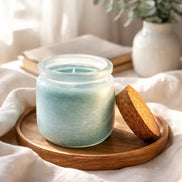 Wanderlust Waves Candle in a glass jar on a wooden tray, featuring a cork lid and a soft background.