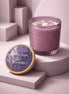 Lavender-hued textured glass candle with cream wax and a purple flower topper.