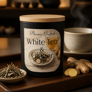 White Tea & Ginger Candle in a sleek black container on a wooden tray with herbs and a cup of tea.