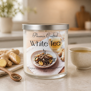 White Tea & Ginger Candle in a glass jar on a kitchen counter with ginger pieces and a cup of tea.