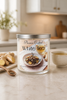 White Tea & Ginger Candle in a glass jar on a kitchen counter with ginger pieces and a cup of tea.