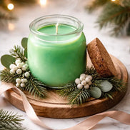 Winter Solstice Glow candle on a wooden tray surrounded by pine leaves and berries.
