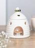 White ceramic beehive tealight warmer with hexagonal cutouts and painted bee knob.