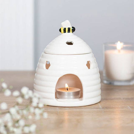 White ceramic beehive tealight warmer with hexagonal cutouts and painted bee knob.